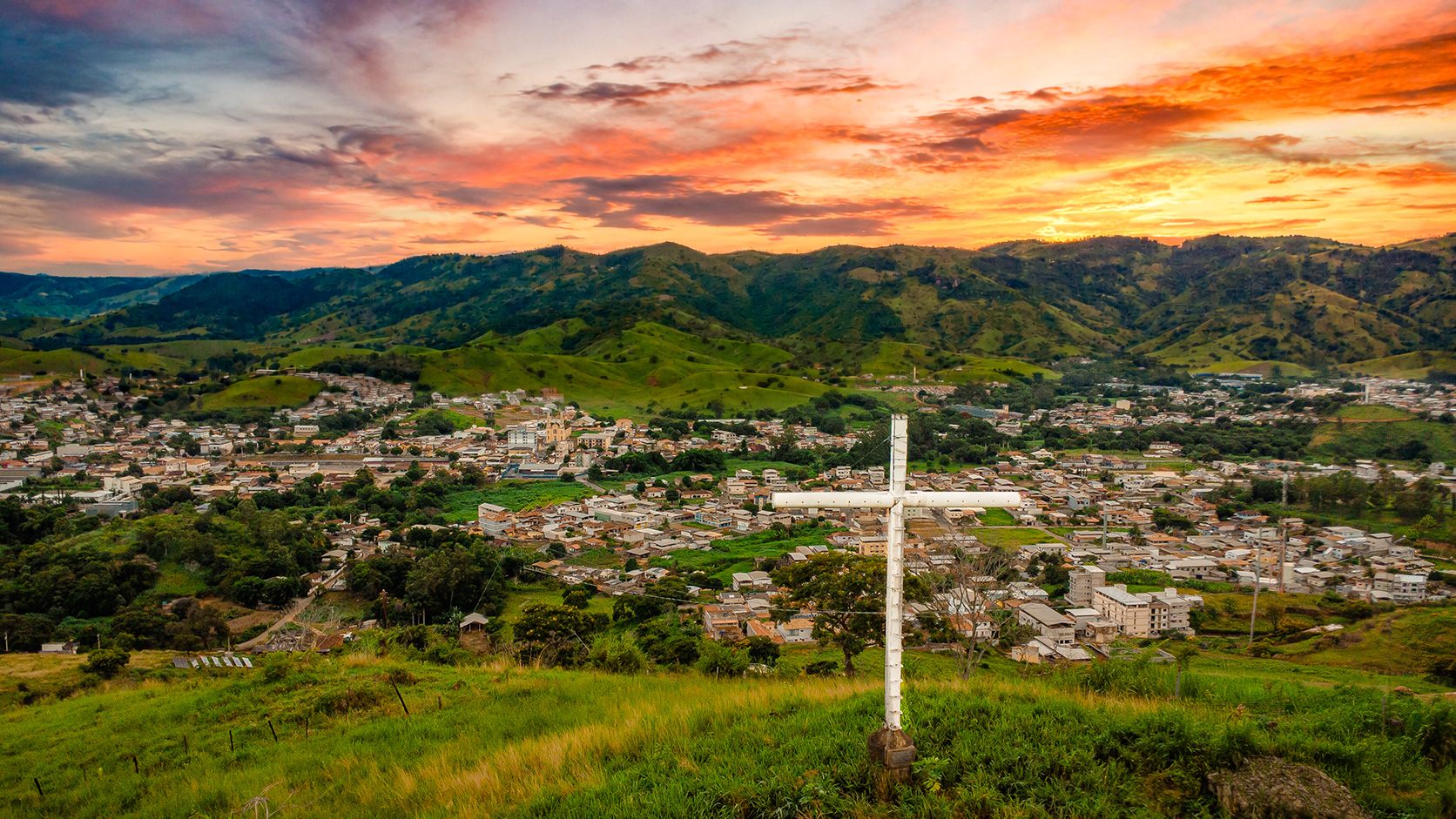 Vista do Cruzeiro de São Geraldo ao pôr do sol, com a cidade e as montanhas ao fundo
